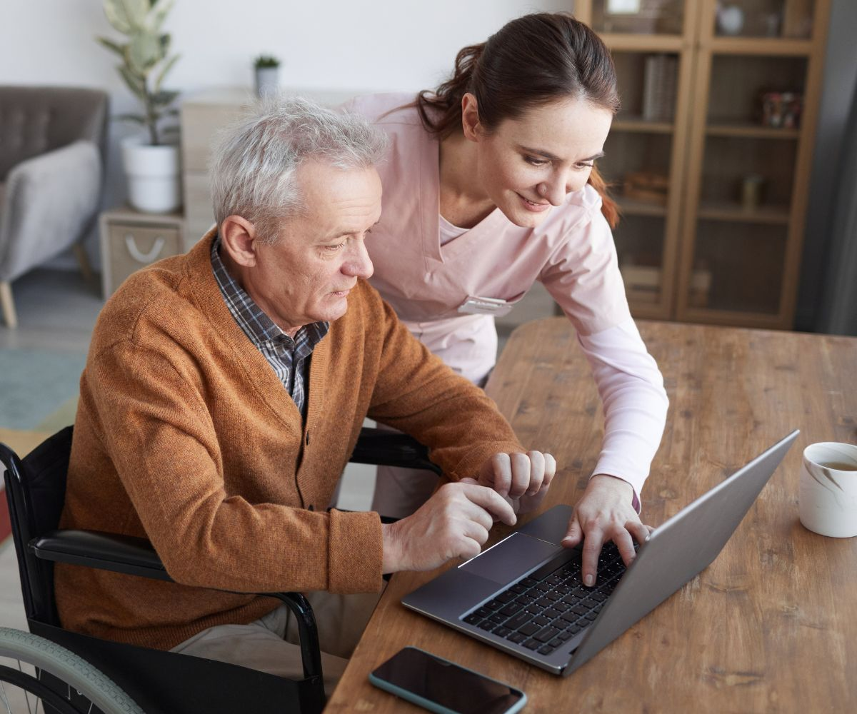Caregiver helping client with laptop