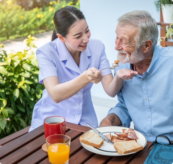 Caregiver providing feeding support to elderly client